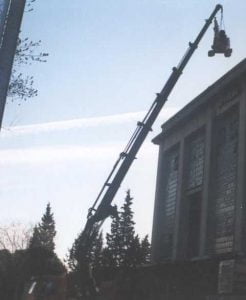 Alt: Grúa de construcción extendida en altura realizando trabajos en un edificio en un día soleado.