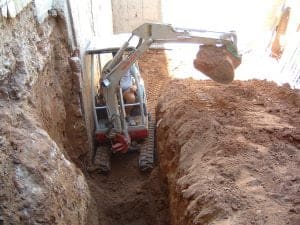 Excavadora pequeña en construcción realizando excavación en terreno.