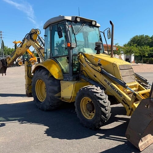 Retro Pala, Marca: NEW HOLLAND, Modelo: B 110 , Año fabricación 2003, Horas: 20.000 Aprox, equipada con dos cazos, 40 y limpieza, Horquillas portapalet, pala de almeja, brazo telescópico, mandos pilotados, matriculada. Maquinaria lista para trabajar.