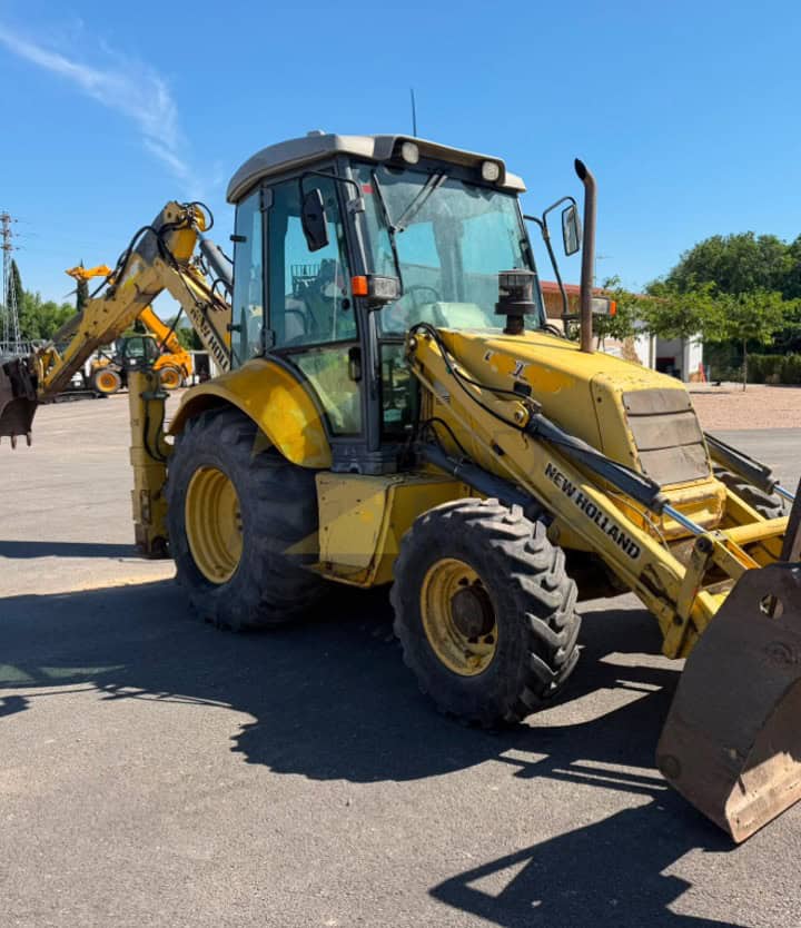 Retro Pala, Marca: NEW HOLLAND, Modelo: B 110 , Año fabricación 2003, Horas: 20.000 Aprox, equipada con dos cazos, 40 y limpieza, Horquillas portapalet, pala de almeja, brazo telescópico, mandos pilotados, matriculada. Maquinaria lista para trabajar.